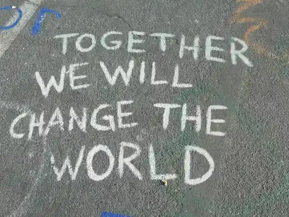 A chalk drawing containing the text "together we can change the world"